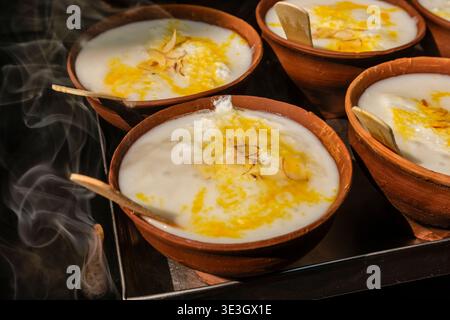 Primo piano dei tradizionali dessert Malai Yo serviti in ciotole di terracotta con zafferano e noci in una strada a Varanasi. Foto Stock