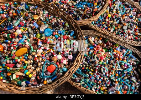 Grandi cesti di vimini pieni di migliaia di perle di vetro colorate e pietre sono offerti in un mercato di Varanasi. Foto Stock