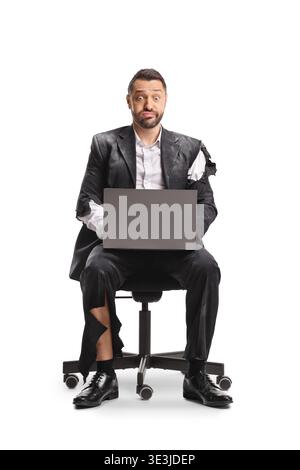 Uomo d'affari esausto in una tuta strappata seduto con un portatile isolato su sfondo bianco Foto Stock