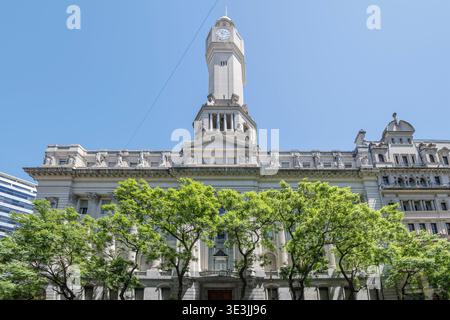 Paesaggio urbano con edifici ministeriali storici dietro gli alberi di avenida de Mayo, capitale dell'Argentina, girato alla luce dell'estate a Buenos Aires, Foto Stock
