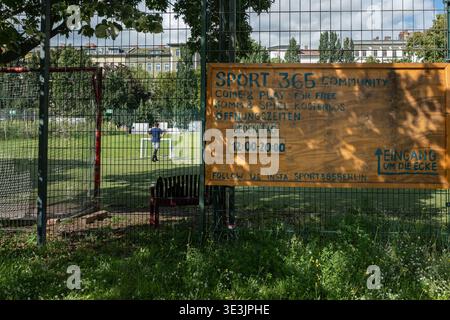 Bambini che giocano a calcio dietro la recinzione metallica a rete nel Gorlitzer Park, Berlino - Germania. Foto Stock
