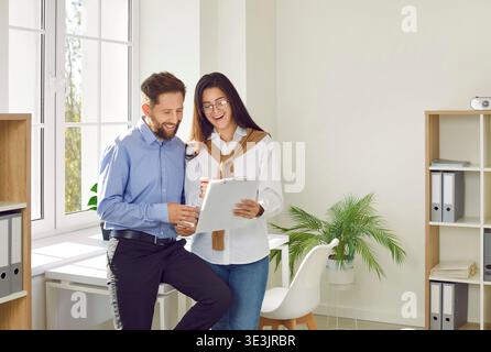 Colleghi che discutono il progetto sugli appunti in un ufficio moderno e luminoso, concentrati sul lavoro di squadra Foto Stock