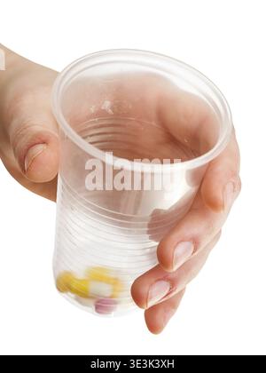 Tazza di plastica con una porzione di pillole in mano, su sfondo bianco Foto Stock