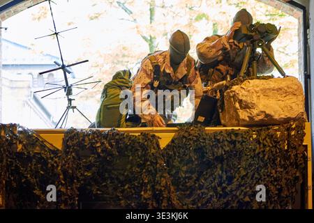 Due soldati che indossano uniformi mimetiche nel deserto e balaclavi fanno un punto di osservazione posizionato in un'apertura della finestra. Il soldato a destra sembra Foto Stock