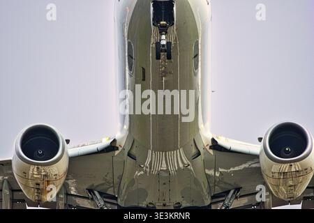 Uno scatto verticale professionale che mostra la pancia di un aereo passeggeri. La prospettiva mette in evidenza la simmetria dei motori a reazione, il gea a punta allungata Foto Stock