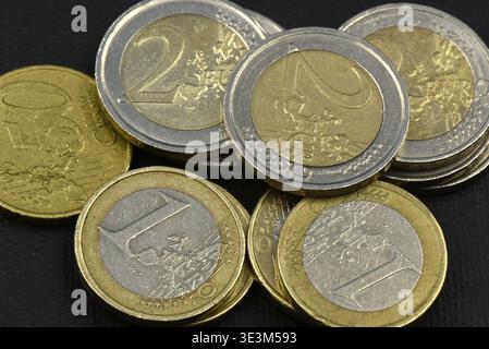 Primo piano di diverse monete in euro con monete da 50 centesimi, monete da un euro e monete da due euro su sfondo nero Foto Stock