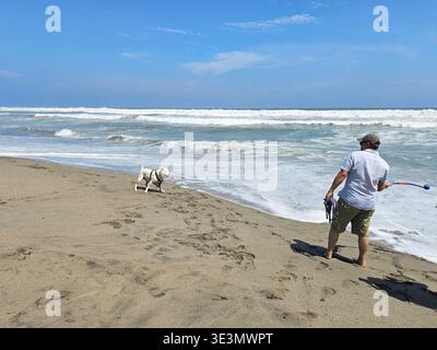 Un uomo latino single di 40 anni ama la spiaggia con il suo cane emotivo per lavorare sulla depressione e l'ansia Foto Stock