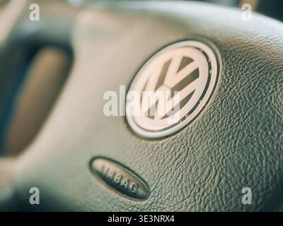 Riga, Lettonia - 22 marzo 2026: Primo piano macro di un volante Volkswagen con l'iconico logo e l'airbag in rilievo. D. Auto di alta qualità Foto Stock