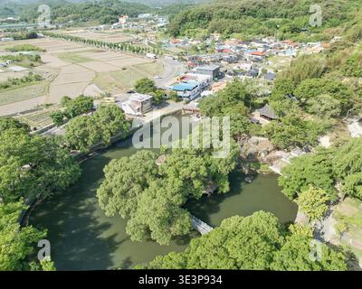 Vista aerea del Padiglione Mujinjeong ad Haman, Corea del Sud. Mostra un'architettura tradizionale circondata da un tranquillo laghetto, alberi verdi e un ponte. Foto Stock