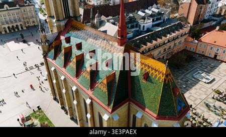 Veduta aerea del vivace tetto a motivi geometrici della Chiesa del nome di Maria si staglia contro le nude ombre della piazza circostante, Сад, Vojvodina, Foto Stock