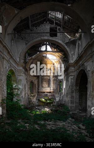 La vista della luce del sole perfora i resti scheletrici di una chiesa dimenticata, illuminando macchie di muschio verde vibrante aggrappato alla pietra intemprata, Parma, Em Foto Stock