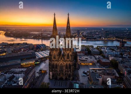 Vista aerea della maestosa Cattedrale di Colonia che perfora lo skyline al crepuscolo, le sue guglie gotiche contrastano con il tranquillo fiume Reno, Colonia, Nort Foto Stock