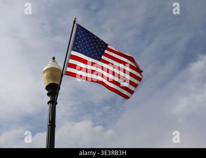 Bandiera nazionale degli Stati Uniti che sventola in aria su Street Light con sfondo Blue Sky a Carmel, IN, USA Foto Stock
