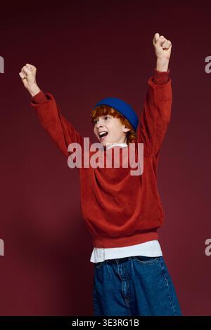 Allegro ragazzo con i capelli rossi esprime eccitazione mentre indossa un abbigliamento casual alla moda. Foto Stock