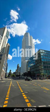 Berlino, Germania - 18 agosto 2025: Il moderno grattacielo si erge sulla strada della città sotto il cielo azzurro. Foto Stock