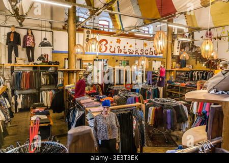 Una vista interna del negozio di seconda mano e upcycling “Buntwäsche” sul sito di Feinkost a Lipsia-Connewitz: Appendiabiti, manichini e lampade a sospensione in un ex salone industriale. Lipsia, Sassonia, Germania Foto Stock