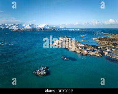 Vista aerea dell'isola di Sommaroy con mare turchese e piccole case costiere, montagne innevate sullo sfondo, Norvegia. Foto Stock