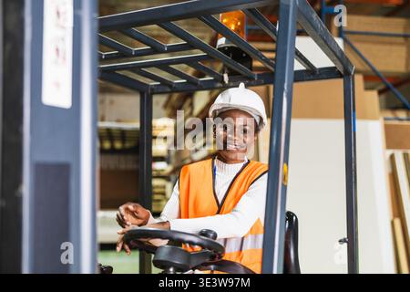 Lavoratrice che utilizza un carrello elevatore a forche in un magazzino di legno Foto Stock