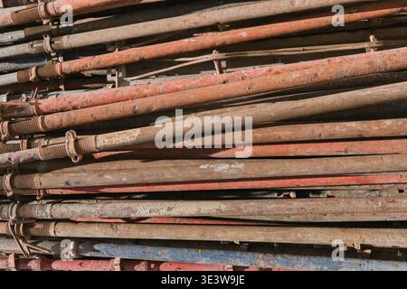 Tubi per impalcature in metallo arrugginito impilati, fondo in texture industriale Foto Stock