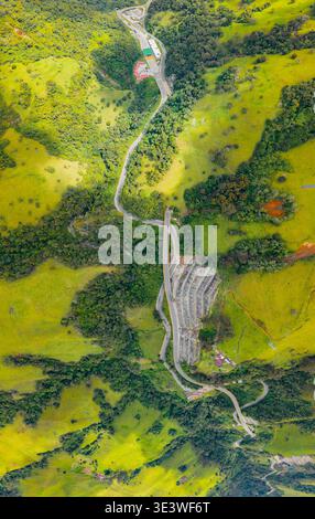 Veduta aerea dell'autostrada la linea, che si snoda attraverso lussureggianti montagne verdi in Colombia, mostrando un'impressionante ingegneria in mezzo a splendidi paesaggi naturali Foto Stock