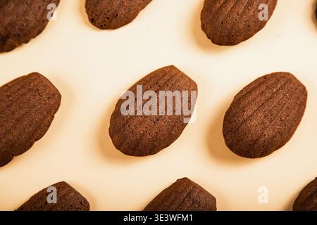 Una vista dall'alto verso il basso di deliziose madeleine di cioccolato disposte su uno sfondo neutro e di colore chiaro. Il motivo mostra la sua forma unica simile a una conchiglia Foto Stock