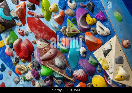 Colorato muro di Bouldering al coperto con varie strutture per arrampicata per l'allenamento in palestra e per l'allenamento delle abilità Foto Stock