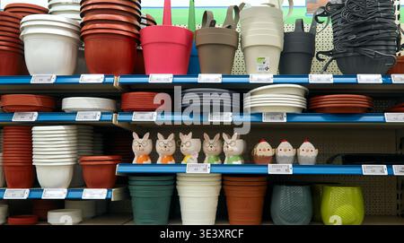 Burgas, Bulgaria - 24 marzo 2026: Varietà di vasi di fiori in plastica e ceramica accanto a statuette decorative disposte su scaffali in un'area di vendita al dettaglio Foto Stock