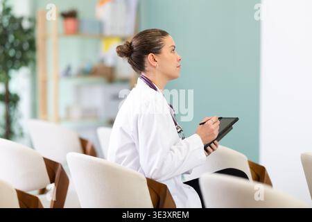 Studentessa di medicina che ascolta la lezione in classe con il tablet Foto Stock