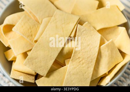Asciugare gli spaghetti organici larghi in una ciotola per cuocere la zuppa Foto Stock