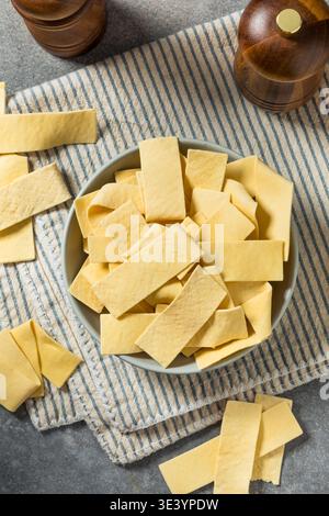 Asciugare gli spaghetti organici larghi in una ciotola per cuocere la zuppa Foto Stock