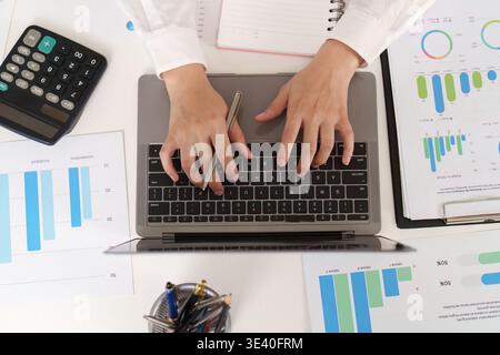 Contabile che scrive su un laptop con documenti finanziari Foto Stock