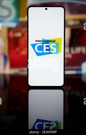 Logo internazionale CES visualizzato sullo schermo di uno smartphone con sfondo sfocato della fiera, che rappresenta l'innovazione dell'elettronica di consumo e la mobilità Foto Stock