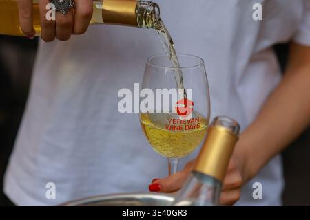Al Festival del vino di Yerevan, che serve momento come vino bianco frizzante viene versato in un bicchiere di degustazione di marca a Yerevan, Armenia. Foto Stock