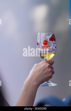 Al Festival del vino di Yerevan, un bicchiere di vino bianco marchiato si è tenuto in un momento ravvicinato durante l'evento a Yerevan, in Armenia. Foto Stock