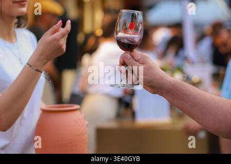Al Festival del vino di Yerevan, un bicchiere di vino bianco marchiato viene sollevato per un brindisi durante il festival di Yerevan, in Armenia. Foto Stock