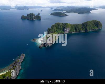Vista aerea delle isole calcaree tropicali con vegetazione lussureggiante e piccole barche nelle acque turchesi dell'isola di Shimizu, Filippine. Foto Stock