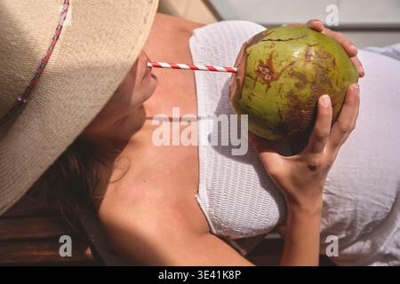 Donna che si gusta una rinfrescante bevanda al cocco all'aperto in una giornata di sole Foto Stock