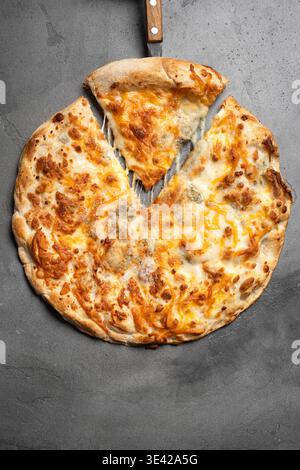Pizza al formaggio con formaggio fuso su sfondo grigio in cemento, vista dall'alto. Fetta di deliziosa pizza al formaggio fresca primo piano con consistenza dettagliata. Foto Stock