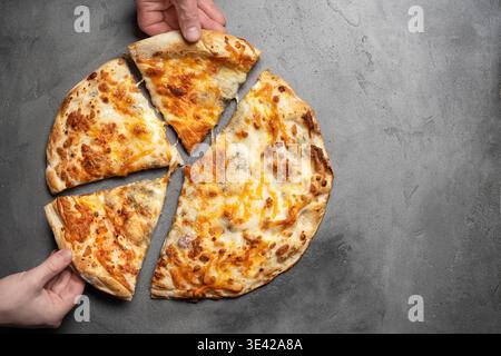 Afferrare le mani fette di pizza su sfondo grigio in cemento, vista dall'alto, spazio di copia. Persone che prendono pezzi di deliziosa pizza al formaggio, amici o familiari Foto Stock