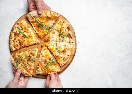 Afferrare le mani fette di pizza su sfondo bianco, vista dall'alto, spazio di copia. Persone che prendono pezzi di deliziosa pizza al formaggio, modello concettuale. Foto Stock