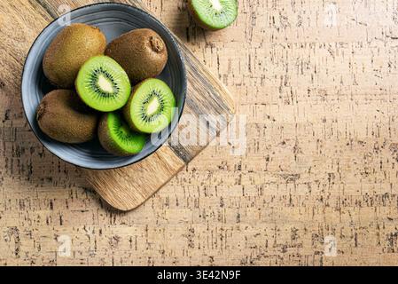 Frutta kiwi su sfondo in legno, vista dall'alto, spazio copia. Frutta intera e mezzo pezzetti di kiwi verde nel recipiente. Kiwi maturo fresco. Sano sano sano sano sano TEM Foto Stock