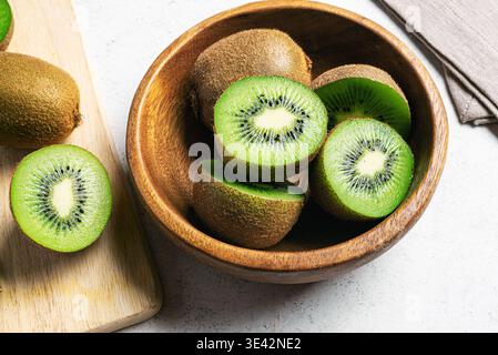 Frutta kiwi su sfondo di legno. Frutta intera e mezzo pezzetti di kiwi verde nel recipiente. Kiwi fresco e maturo. Frutta tropicale. Frutta biologica. Mangiare sano Foto Stock