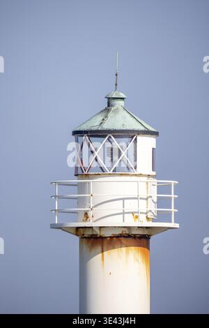 Un dettaglio dettagliato di un faro splendidamente invecchiato che mette in mostra il suo fascino rustico sotto un cielo blu cristallino Foto Stock
