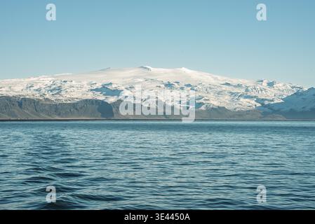 Ghiacciaio e vulcano Eyjafjallajökull visti dal mare nell'Islanda meridionale. Un'ampia vista della calotta glaciale e delle creste vulcaniche sotto un cielo azzurro. Foto Stock