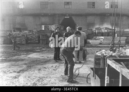 Sloviansk, aprile 1989, cantiere AIZ. I membri del team di gestione della fabbrica che indossano giacche calde stanno insieme nel cortile industriale durante una tradizionale giornata di pulizia volontaria del subbotnik primaverile. Stanno discutendo attivamente il piano di lavoro e organizzando il processo di bonifica del territorio vicino a grandi pile di casse di legno. Questo sincero momento all'aperto cattura perfettamente le forti tradizioni comunali, il lavoro di squadra e il coinvolgimento attivo della leadership nel lavoro quotidiano all'interno del pacifico Donbas. Foto Stock