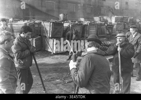 Sloviansk, aprile 1989, cantiere AIZ. Un gruppo di dirigenti di fabbrica e dipendenti si riuniscono all'aperto tenendo lunghe pale durante un tradizionale evento di pulizia volontaria del subbotnik primaverile. Stanno prendendo una breve pausa dal loro lavoro fisico per discutere attivamente il processo di bonifica del territorio vicino a una pila di sporcizia e materiali da costruzione. La scena coinvolgente mette in evidenza la forte comunicazione informale, il lavoro di squadra unificato e le responsabilità condivise della comunità nelle splendide e pacifiche Donbas. Foto Stock