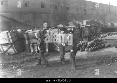 Sloviansk, aprile 1989, cantiere AIZ. Due responsabili di fabbrica scambiano una stretta di mano ferma e amichevole durante una tradizionale giornata di pulizia volontaria del subbotnik primaverile. Si trovano nel cortile industriale circondato da grandi pile di casse di legno e pesanti isolatori elettrici in ceramica. Questo gesto all'aperto, profondamente simbolico e positivo, cattura perfettamente il rispetto reciproco, la forte cameratismo e lo spirito collettivo unificato della laboriosa leadership dell'impresa sovietica nel bellissimo e pacifico Donbas. Foto Stock