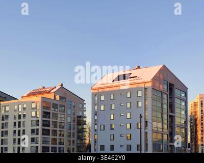 Moderni edifici di appartamenti con pannelli solari su un tetto innevato sotto un cielo azzurro e limpido in una splendida serata invernale in Finlandia Foto Stock