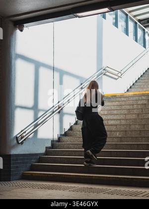 donna che sale le scale in un passaggio sotterraneo Foto Stock
