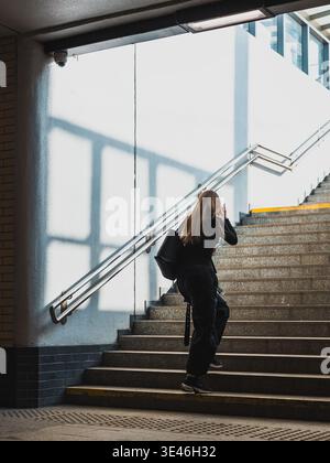 donna che sale le scale in un passaggio sotterraneo Foto Stock